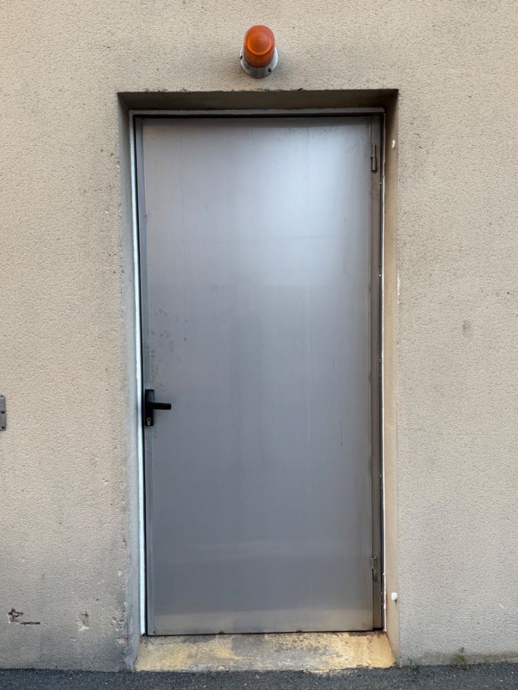 Porte métallique en acier sur mesure posée sur bâtiment industriel